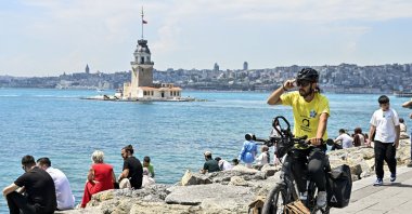 Semih Gürbüz poses with his bicycle near Kız Kulesi after completing a seven-country journey, Istanbul, Türkiye, May 28, 2026. (AA Photo)