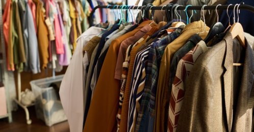 Clothing racks display assorted vintage garments hanging in a thrift shop. (Shutterstock Photo)