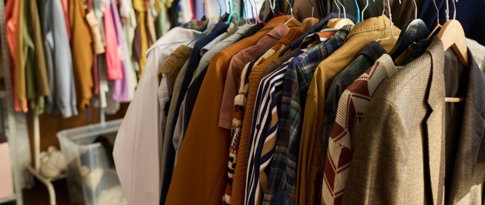 Clothing racks display assorted vintage garments hanging in a thrift shop. (Shutterstock Photo)