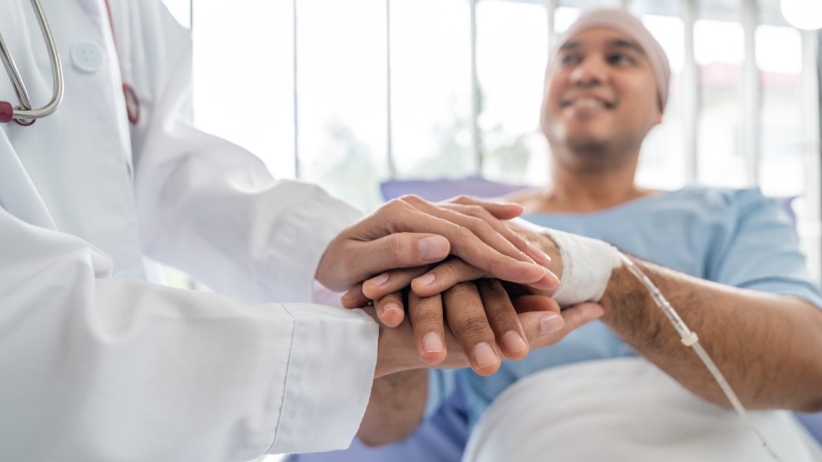 A male cancer patient in a wheelchair receives IV therapy while a doctor provides support. (Shutterstock Photo)