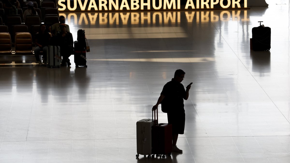 A traveler with luggage looks at a mobile phone after arriving at the international arrivals terminal in Suvarnabhumi Airport in Samut Prakan province, on the outskirts of Bangkok, Thailand, May 4, 2026. (EPA Photo)