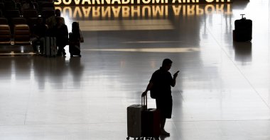 A traveler with luggage looks at a mobile phone after arriving at the international arrivals terminal in Suvarnabhumi Airport in Samut Prakan province, on the outskirts of Bangkok, Thailand, May 4, 2026. (EPA Photo)