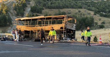 Police officers stand next to the damaged bus at the site of an accident after it crashed into highway barriers in Denizli province, Türkiye, May 31, 2026. (AA Photo)