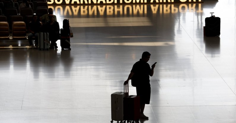 A traveler with luggage looks at a mobile phone after arriving at the international arrivals terminal in Suvarnabhumi Airport in Samut Prakan province, on the outskirts of Bangkok, Thailand, May 4, 2026. (EPA Photo)