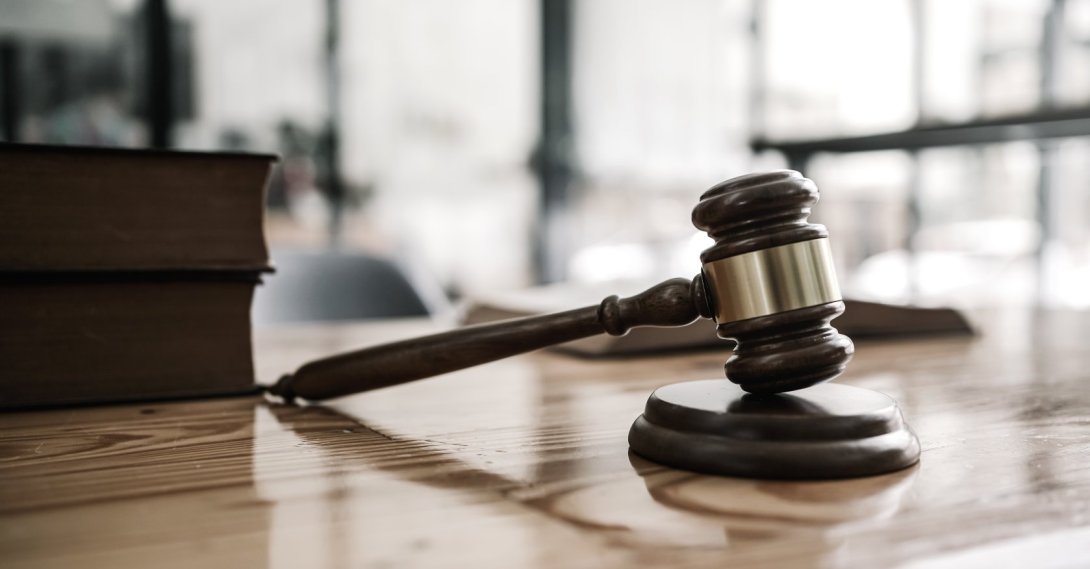 A wooden gavel and law book are seen on a desk. (Shutterstock Photo)