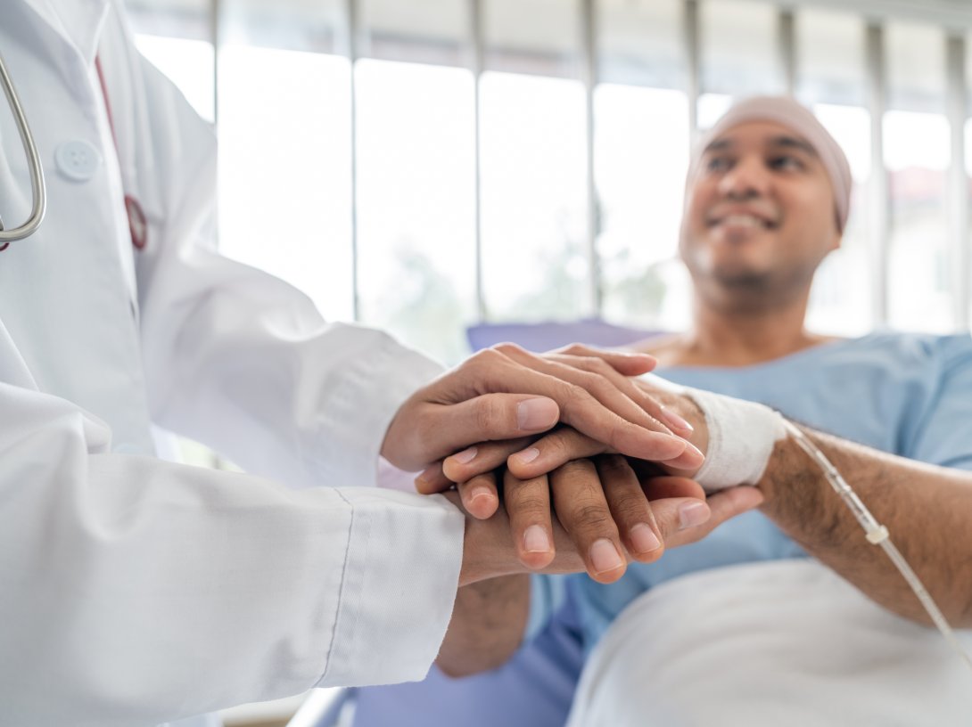 A male cancer patient in a wheelchair receives IV therapy while a doctor provides support. (Shutterstock Photo)