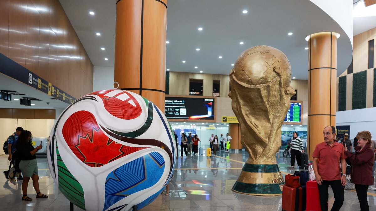 Passengers look at a giant model of the football called "Trionda" and a replica of the World Cup trophy, which are displayed at Mexico City International Airport, ahead of the World Cup starting on June 11, Mexico City, Mexico, May 15, 2026. (Reuters Photo)