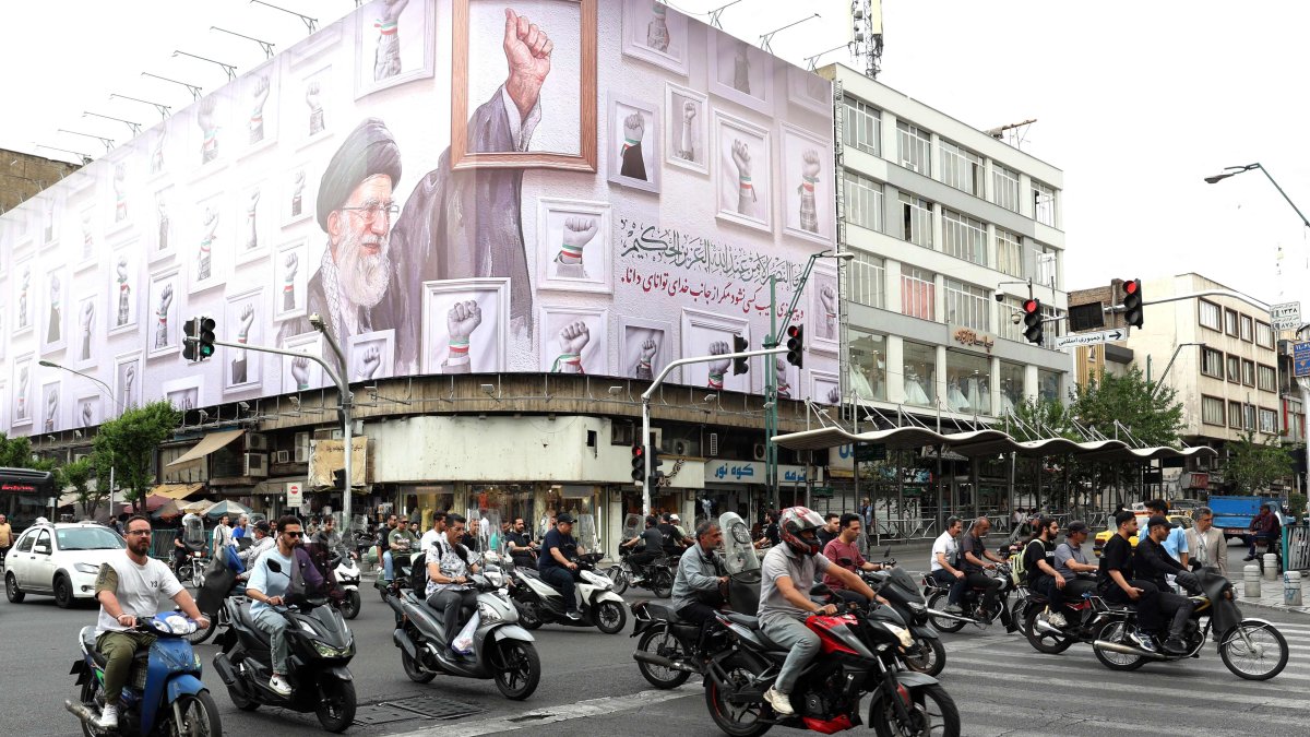 Iranians drive past a huge billboard carrying the image of the late Iranian supreme leader Ayatollah Ali Khamenei, in Tehran on May 5, 2026. (AFP File Photo)