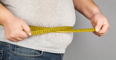 A man measures his belly with a measuring tape. (Shutterstock Photo)