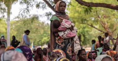 A woman holds her baby outside the registration center for new refugees on the outskirts of the Korsi Refugee Camp in Birao, Central African Republic, March 26, 2026. (AP Photo)