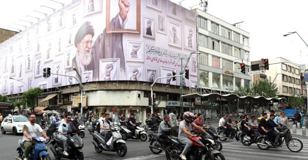 Iranians drive past a huge billboard carrying the image of the late Iranian supreme leader Ayatollah Ali Khamenei, in Tehran on May 5, 2026. (AFP File Photo)