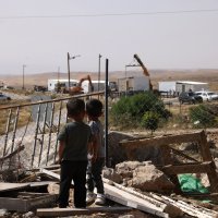Palestinian children watch as new prefabricated Jewish outpost homes are secured into place along a road that leads toward the Palestinian village of Umm al-Khair, in Israeli-occupied West Bank, Palestine, May 20, 2026. (AFP Photo)