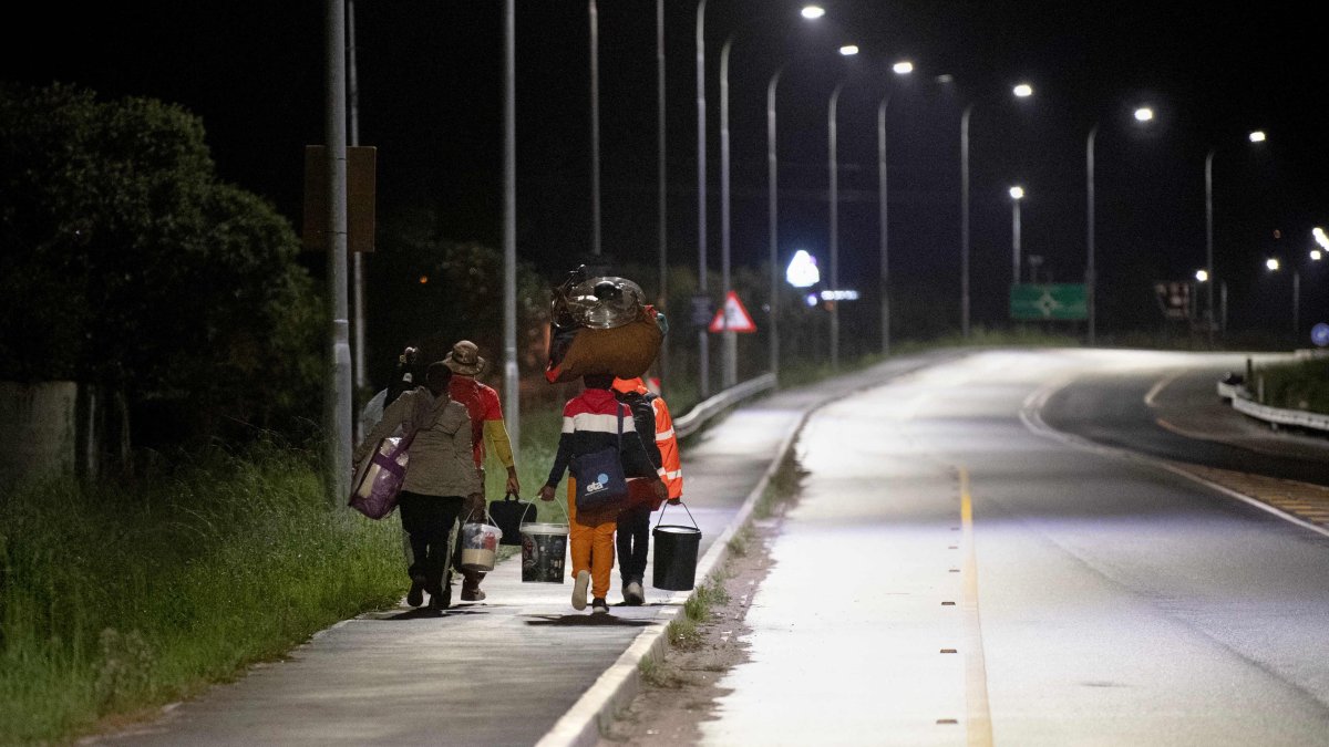 Immigrants carrying their belongings walk on a street after they were threatened in the communities in which they live, Stanford, South Africa, June 2, 2026. (AFP Photo)