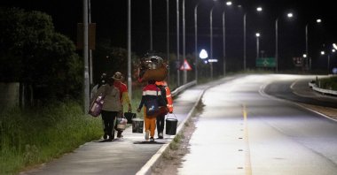 Immigrants carrying their belongings walk on a street after they were threatened in the communities in which they live, Stanford, South Africa, June 2, 2026. (AFP Photo)