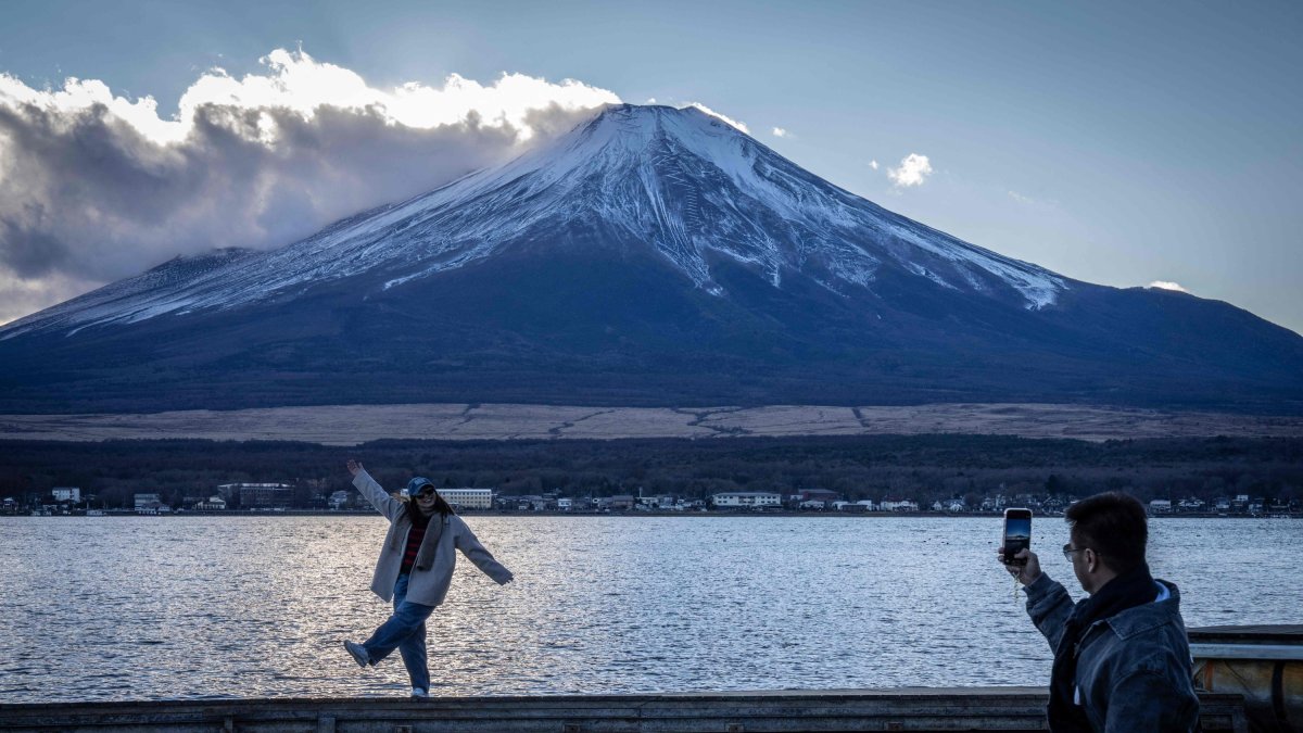 People take photographs with Mount Fuji at Lake Yamanakako, Yamanashi Prefecture, Japan, Dec. 5, 2025. (AFP Photo)
