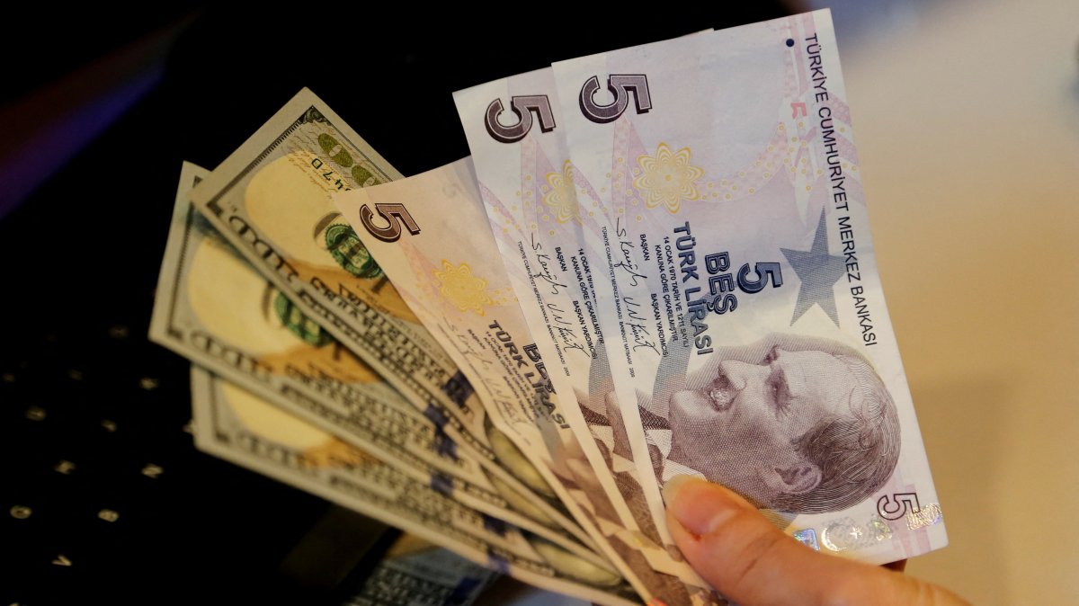 A money changer holds Turkish lira and U.S. dollar banknotes at a currency exchange office in Ankara, Türkiye, Dec. 16, 2021. (Reuters Photo)