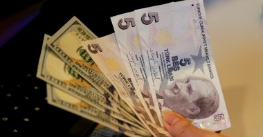 A money changer holds Turkish lira and U.S. dollar banknotes at a currency exchange office in Ankara, Türkiye, Dec. 16, 2021. (Reuters Photo)