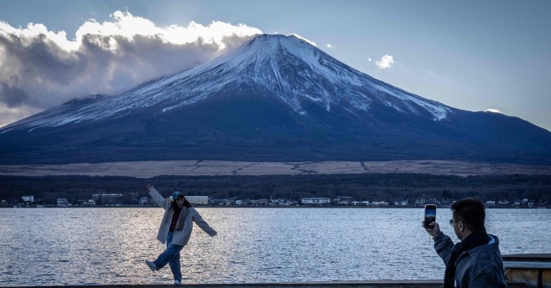 People take photographs with Mount Fuji at Lake Yamanakako, Yamanashi Prefecture, Japan, Dec. 5, 2025. (AFP Photo)