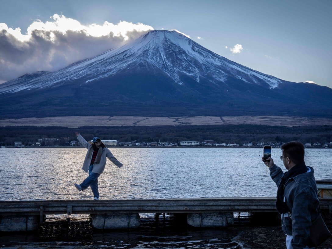 People take photographs with Mount Fuji at Lake Yamanakako, Yamanashi Prefecture, Japan, Dec. 5, 2025. (AFP Photo)