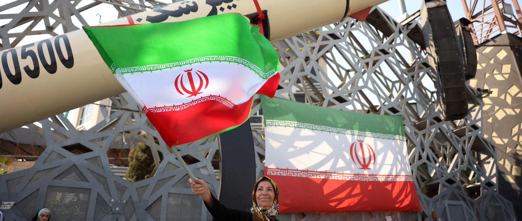 An Iranian woman waves a national flag next to a mock Iranian Kheibarshekan ballistic missile during a rally to show their support and solidarity with Supreme Leader Ayatollah Mojtaba Khamenei, in Tehran, Iran, June 4, 2026. (EPA Photo)