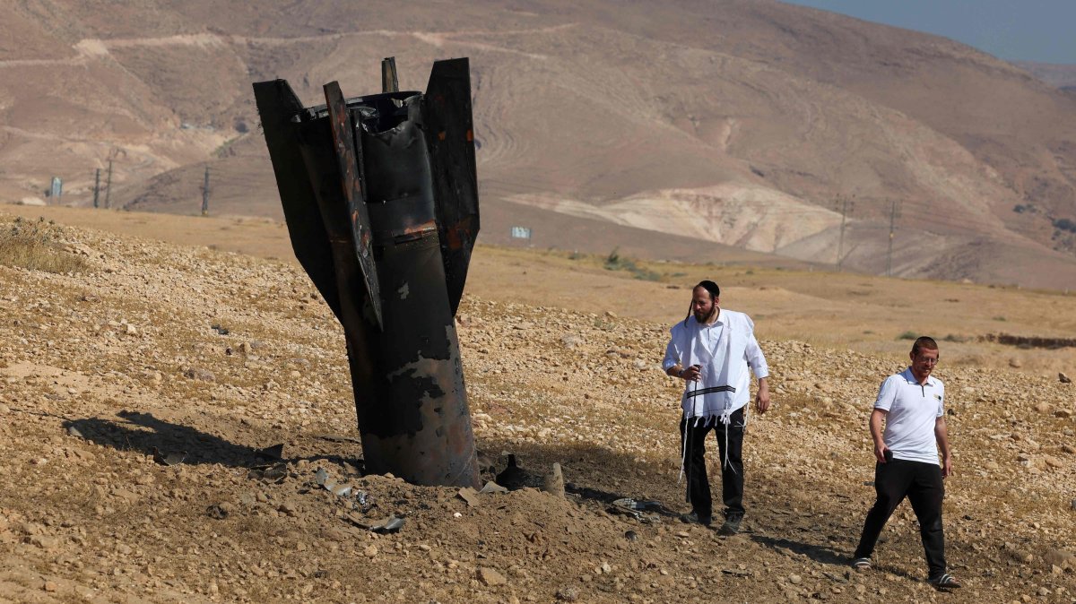 Two men examine a fallen rocket half-buried in the ground on the outskirts of Jericho, Israel-occupied West Bank, Palestine, June 8, 2026. (AFP Photo)