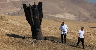 Two men examine a fallen rocket half-buried in the ground on the outskirts of Jericho, Israel-occupied West Bank, Palestine, June 8, 2026. (AFP Photo)