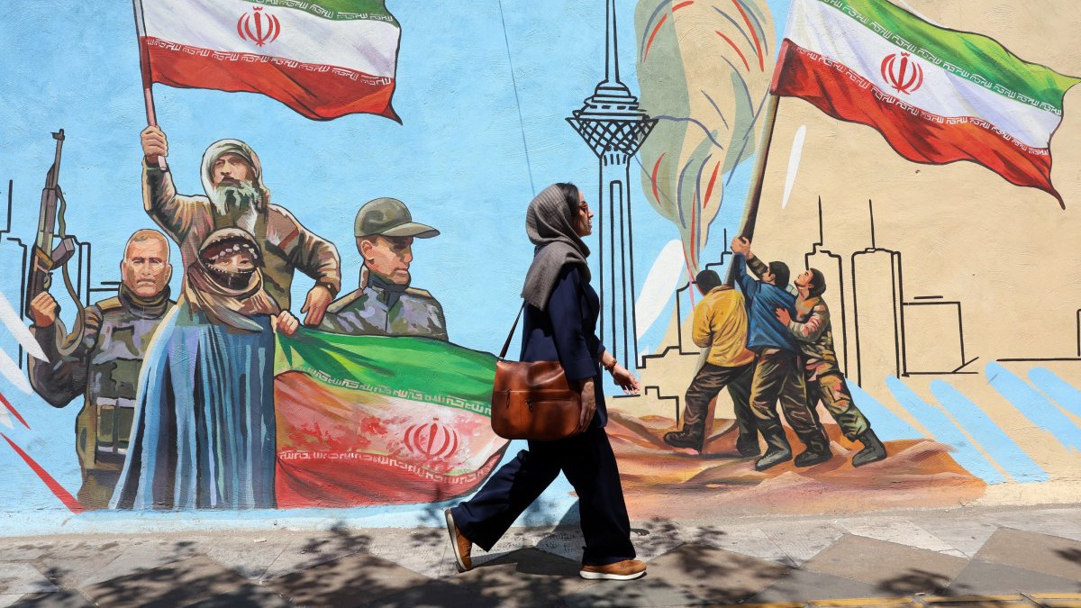 An Iranian woman walks past a mural on a street in Tehran, Iran, June 8, 2026. (EPA Photo)