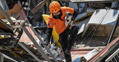 An emergency worker carries a rescue dog while conducting search and rescue operations in a collapsed building after a 7.8 magnitude earthquake in General Santos, Philippines, June 9, 2026. (AFP Photo)