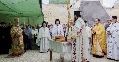 Clergymen and attendees gather near a small table holding loaves of bread under a green canopy at the Chapel of the Ascension to mark the Ascension Day in Jerusalem on May 21, 2026. (AFP File Photo)