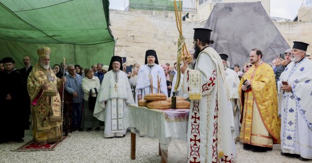Clergymen and attendees gather near a small table holding loaves of bread under a green canopy at the Chapel of the Ascension to mark the Ascension Day in Jerusalem on May 21, 2026. (AFP File Photo)