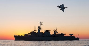 A military plane flies over a warship during a peacekeeping operation in the Black Sea, Aug. 13, 2025. (Shutterstock Photo)