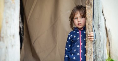 A refugee girl peeks out from a tent at a refugee camp, Idlib, Syria, Feb. 7, 2023. (Shutterstock Photo)