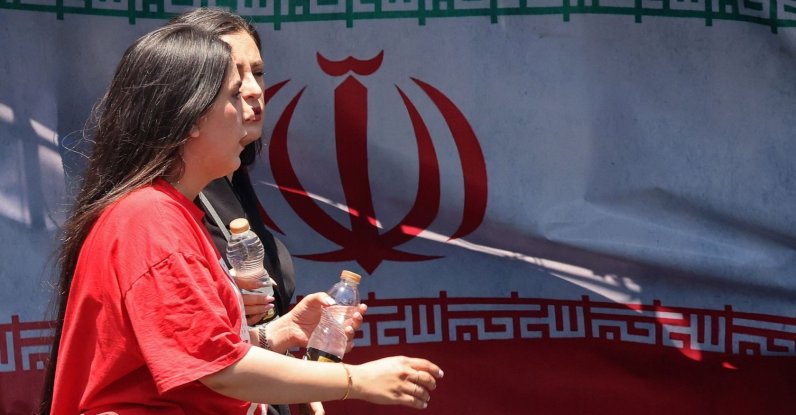 Women walk past Iran's national flag at Vanak Square in Tehran, Iran, June 10, 2026. (AFP Photo)