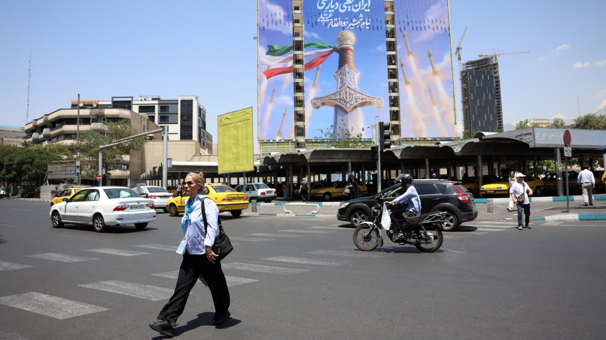 Iranians walk past a large-scale political billboard featuring Iranian missiles and a sword at Vanak Square in Tehran, Iran, June 11, 2026. (EPA Photo)
