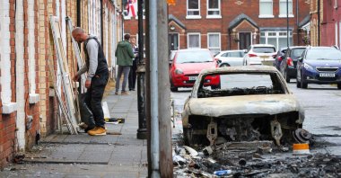 Tradespeople replace front doors of boarded-up houses off the Newtownards Road after two consecutive nights of violence following the June 8 stabbing of Stephen Ogilvie, which triggered the unrest, Belfast, Northern Ireland, June 11, 2026. (AFP Photo)