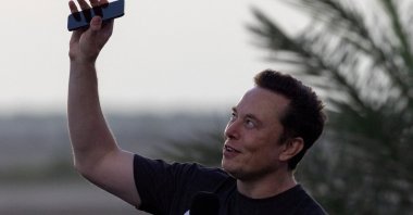 Elon Musk raises his phone toward the sky during a joint news conference with T-Mobile CEO Mike Sievert (not pictured) at the SpaceX Starbase, Brownsville, Texas, U.S., Aug. 25, 2022. (Reuters Photo)