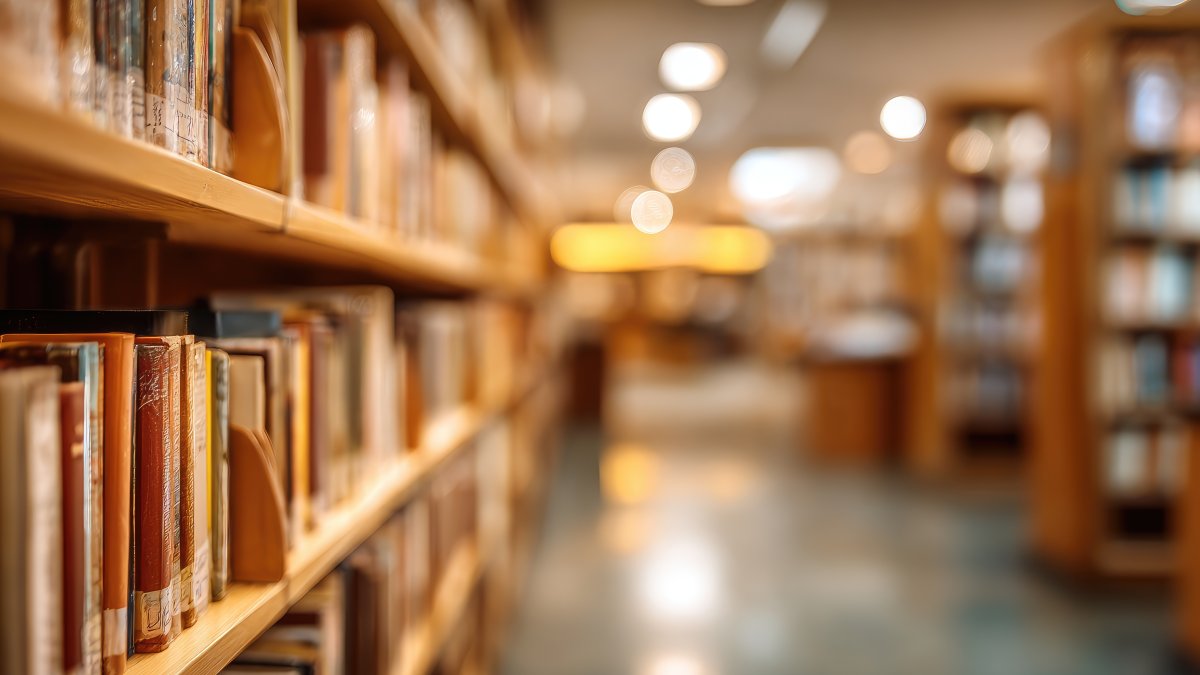 Rows of bookshelves filled with numerous books line a library aisle. (Shutterstock Photo)