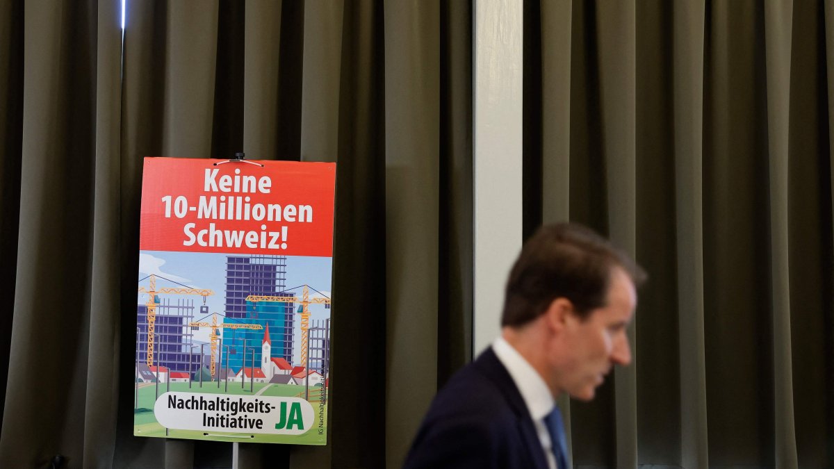 A member of the Swiss People's Party (SVP) walks past an election placard reading "Not a 10-million Switzerland" in Aarberg, Switzerland, June 14, 2026. (AFP Photo)