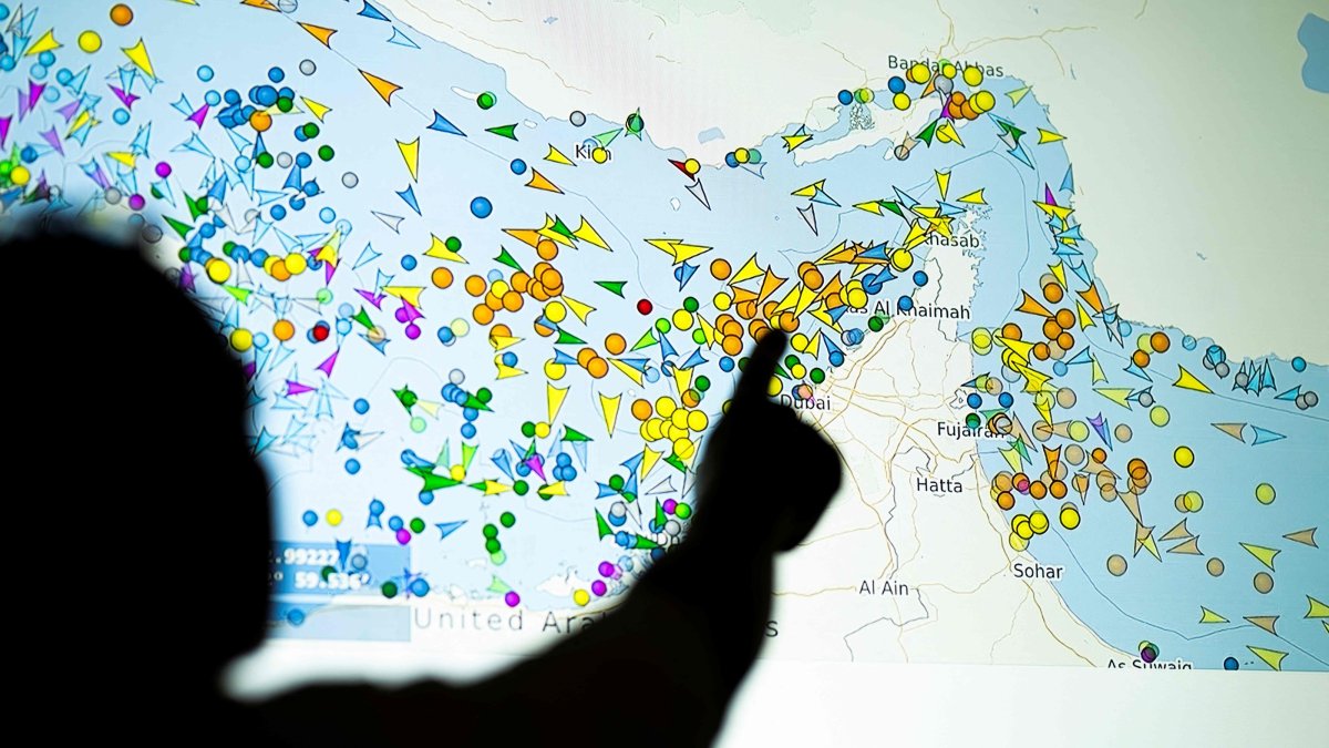 A photo illustration shows a person in front of a large screen displaying vessel movements in the Strait of Hormuz on a ship-tracking website, May 4, 2026. (AFP Photo)