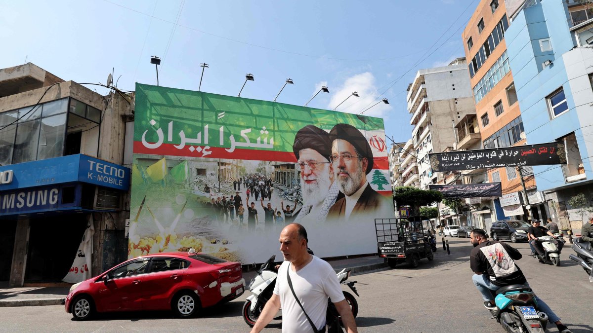 A man walks past a giant billboard depicting the late Iranian leader Ayatollah Ali Khamenei (C), and his son the Iranian Supreme Leader Ayatollah Mojtaba Khamenei, in Dahiyeh, Beirut's southern suburbs, June 15, 2026. (AFP Photo)