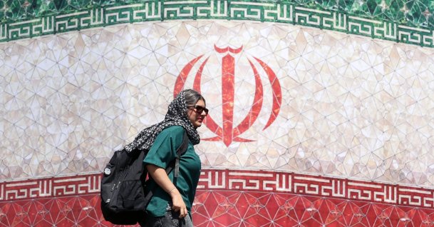 An Iranian woman walks past a billboard featuring Iran's national flag at Enqelab Square in Tehran, Iran, June 14, 2026. (EPA Photo)