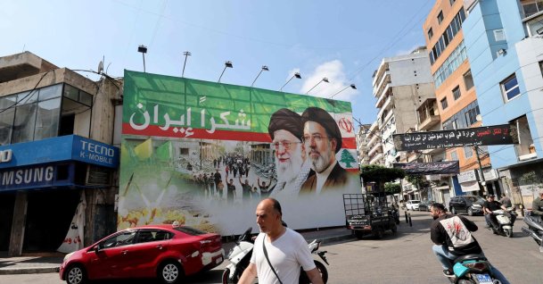 A man walks past a giant billboard depicting the late Iranian leader Ayatollah Ali Khamenei (C), and his son the Iranian Supreme Leader Ayatollah Mojtaba Khamenei, in Dahiyeh, Beirut's southern suburbs, June 15, 2026. (AFP Photo)