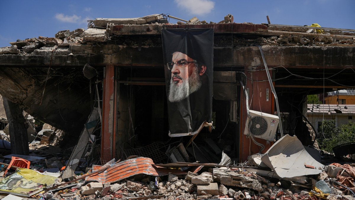 A banner with an image of late Hezbollah leader Hassan Nasrallah hangs from a destroyed building in Jibchit, Nabatieh district, Lebanon, June 16, 2026. (Reuters Photo)