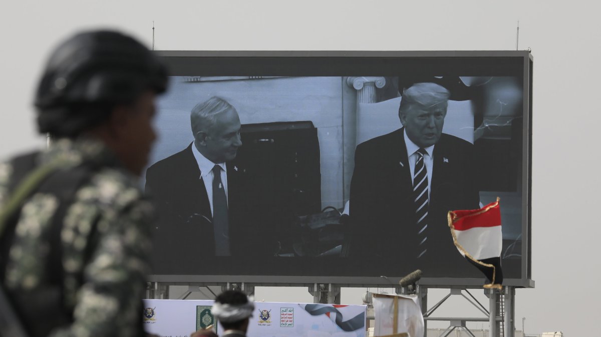 A Houthi soldier stands guard in front of a digital billboard featuring U.S. President Donald Trump and Israeli Prime Minister Benjamin Netanyahu, in Sana'a, Yemen, May 18, 2026. (EPA Photo)