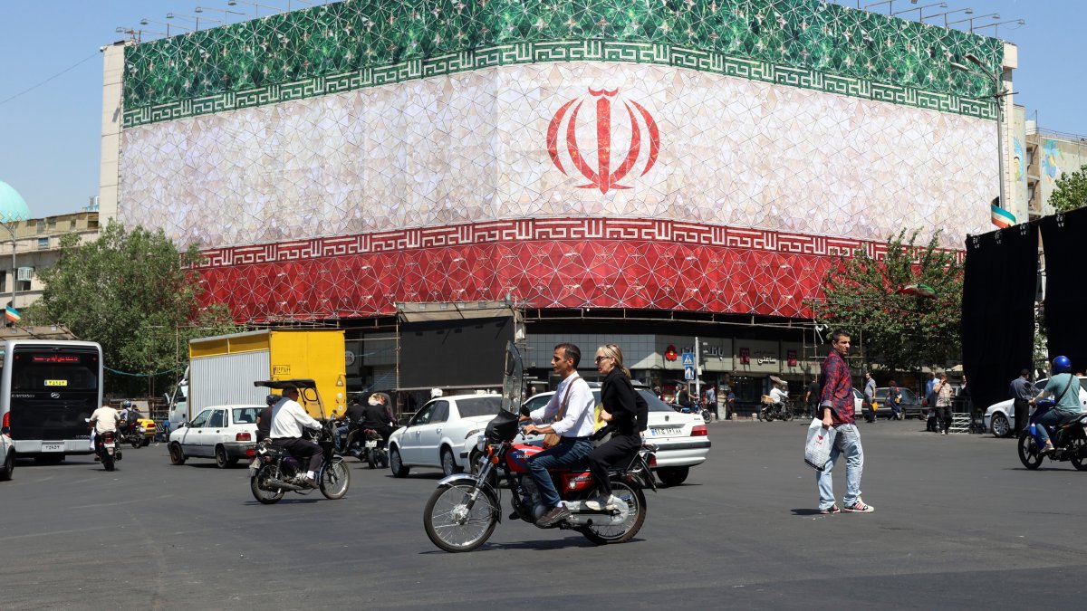 Iranians drive past a billboard featuring Iran's national flag at Enqelab Square in Tehran, Iran, June 14, 2026. (EPA Photo)