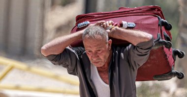 A man carries a suitcase as people retrieve their remaining belongings from the Nur Shams camp for Palestinian refugees, occupied West Bank, Palestine, June 16, 2026. (AFP Photo)