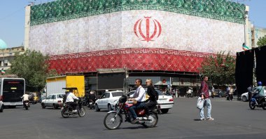 Iranians drive past a billboard featuring Iran's national flag at Enqelab Square in Tehran, Iran, June 14, 2026. (EPA Photo)