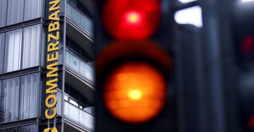 Traffic lights glow near a logo of Commerzbank at a branch, Cologne, Germany, March 16, 2026. (Reuters Photo)