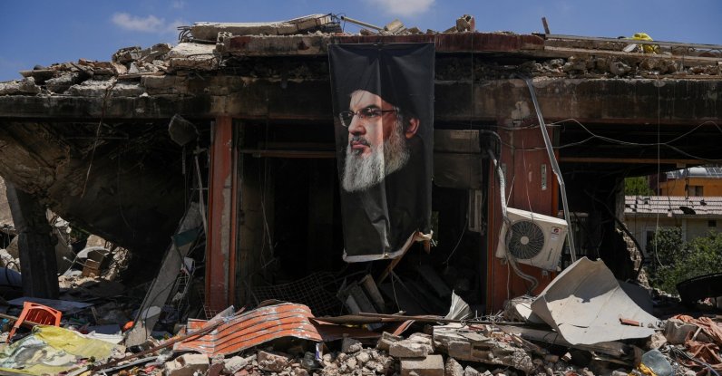 A banner with an image of late Hezbollah leader Hassan Nasrallah hangs from a destroyed building in Jibchit, Nabatieh district, Lebanon, June 16, 2026. (Reuters Photo)