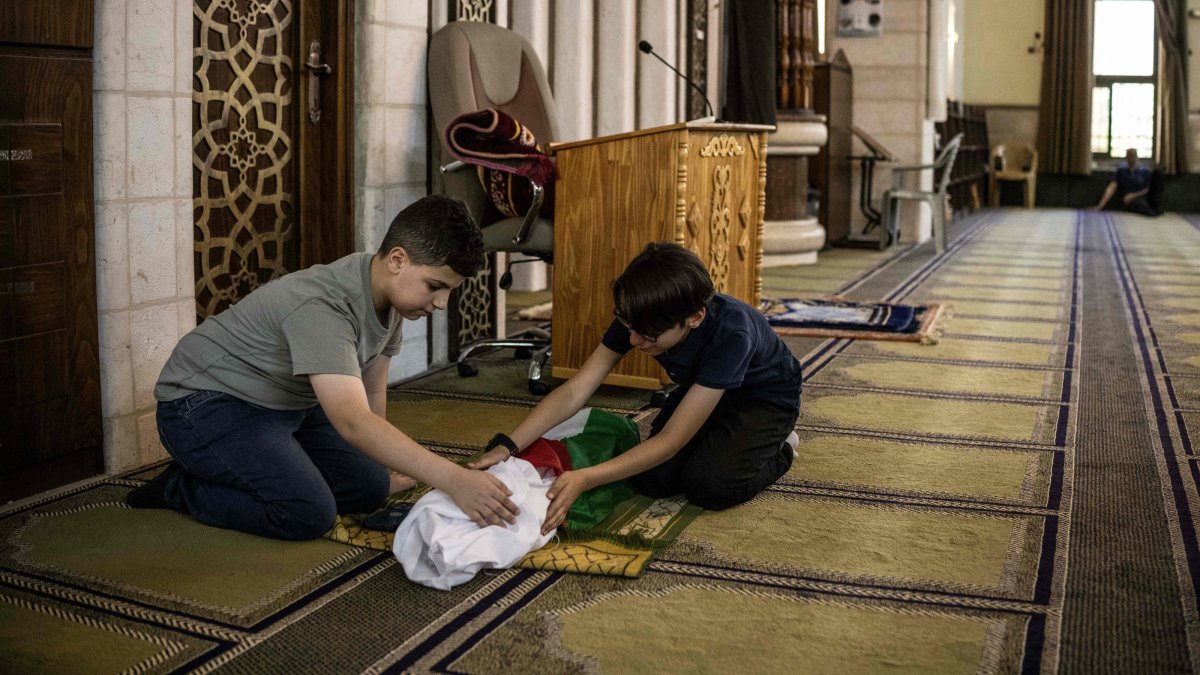 Kinan Abou Haikal (L), the elder brother of seven-month-old baby Sam Fahd Abou Haikal, killed by Israeli gunfire, sits next to his body at the Abou Heisheh Mosque in Hebron, in the occupied West Bank, Palestine, June 6, 2026. (AFP Photo)